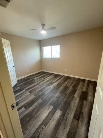 en empty room with wooden floor ceiling fan and window