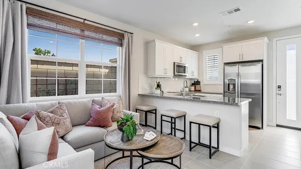 a living room with stainless steel appliances kitchen island granite countertop a couch a dining table and chairs