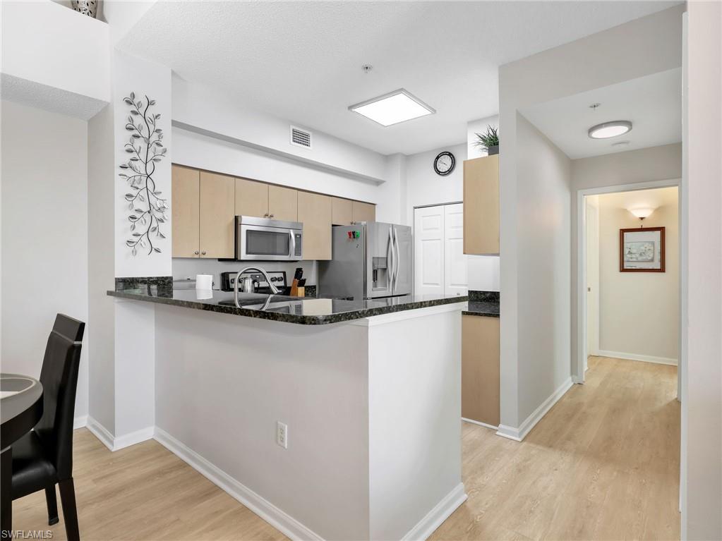 1205 Reserve Way, Unit 302 Naples, FL 34105 - Photo 12 of 31 a kitchen with stainless steel appliances granite countertop a refrigerator and a stove top oven