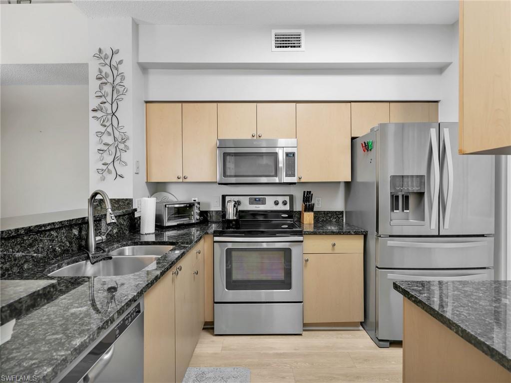 1205 Reserve Way, Unit 302 Naples, FL 34105 - Photo 13 of 31 a kitchen with granite countertop a sink stove and refrigerator