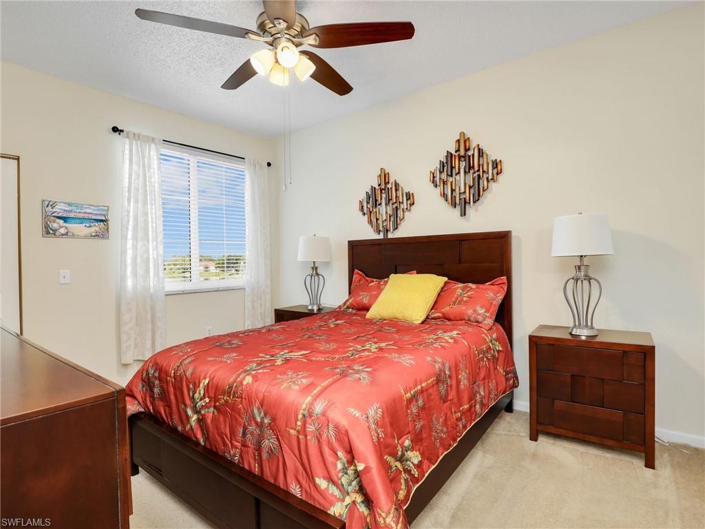 1205 Reserve Way, Unit 302 Naples, FL 34105 - Photo 16 of 31 a bedroom with a bed and a chandelier