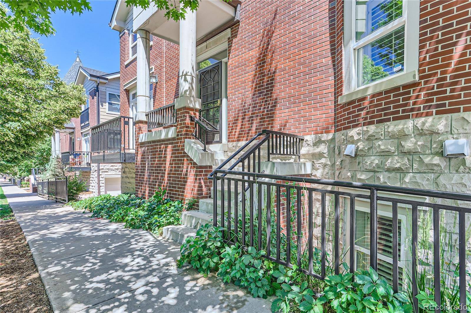 15 Jackson Street, Unit A Denver, CO 80206 - Photo 4 of 17 a view of a brick house with many windows plants and large trees