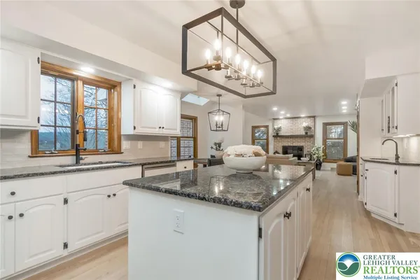 a kitchen with stainless steel appliances granite countertop a sink a oven a dining table and chairs with wooden floor