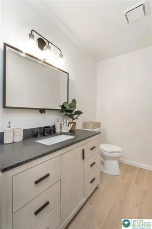 a bathroom with a granite countertop sink and a toilet