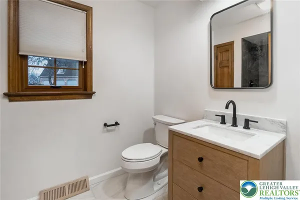 a bathroom with a toilet a sink a vanity and mirror