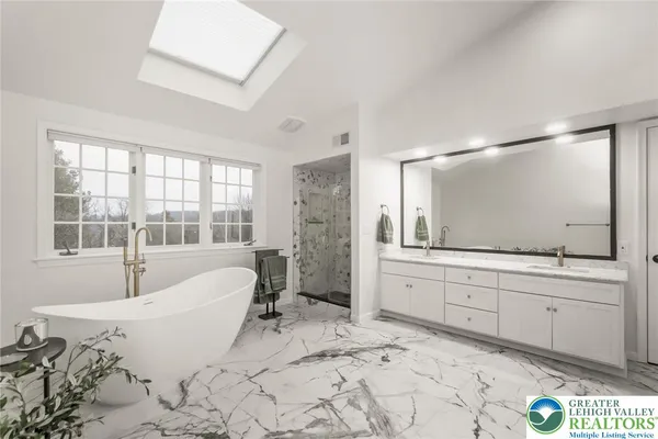 a spacious bathroom with a tub sink and mirror