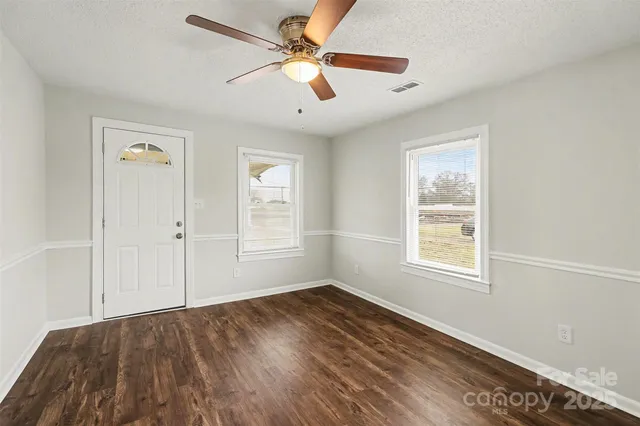 a view of empty room with wooden floor and fan
