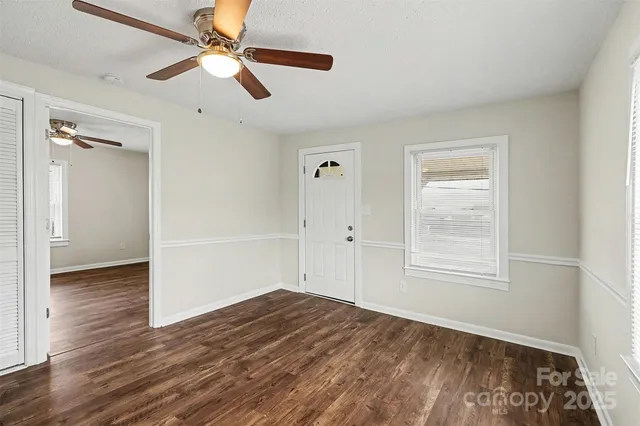 an empty room with wooden floor ceiling fan and windows