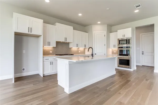 a kitchen with stainless steel appliances granite countertop a refrigerator and a stove top oven