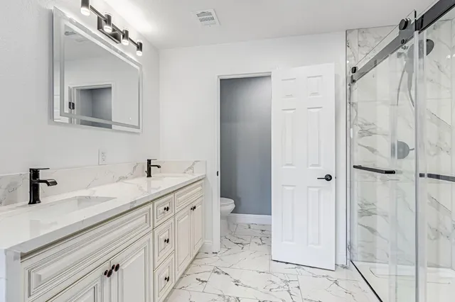 a bathroom with a double vanity sink mirror and shower