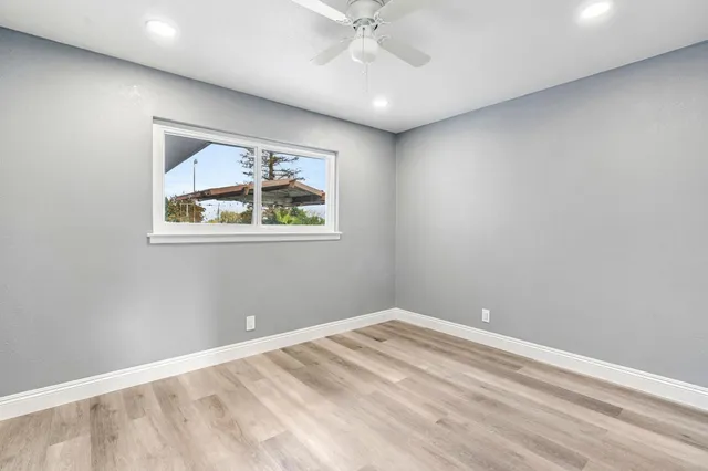 an empty room with a window and a fan