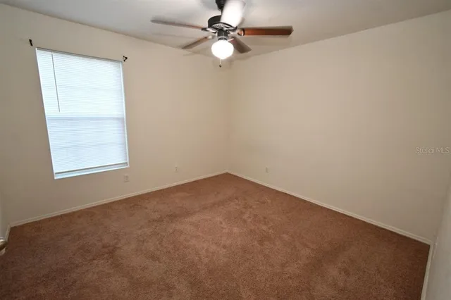 an empty room with closet and a chandelier fan