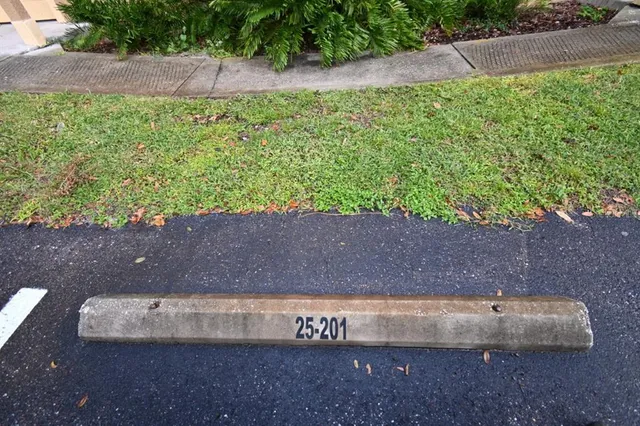 a sign that is sitting on a brick wall with plants