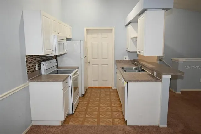 a kitchen with white cabinets and white appliances