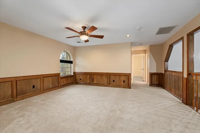 an empty room with chandelier fan and windows