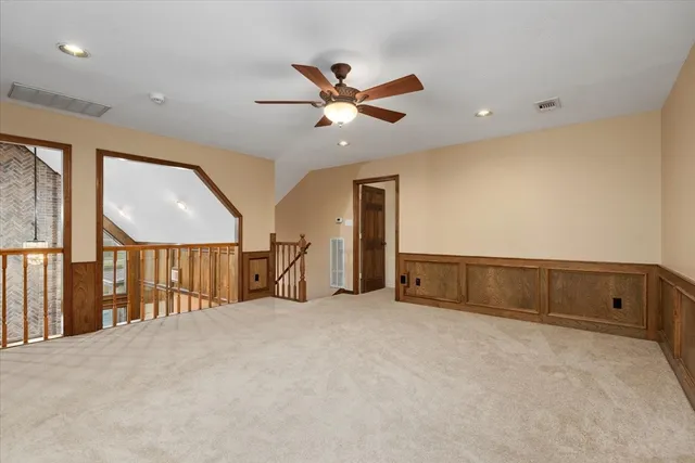 an empty room with ceiling fan and windows
