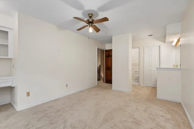 an empty room with a fan & a window