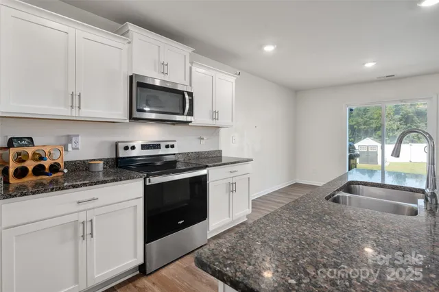 a kitchen with stainless steel appliances granite countertop a sink and a stove