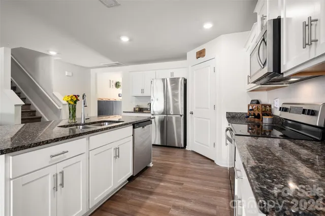 a large kitchen with stainless steel appliances granite countertop a lot of counter space and wooden floors