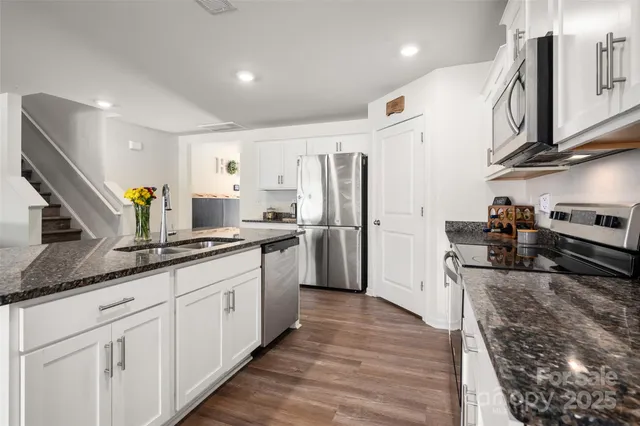 a large kitchen with stainless steel appliances granite countertop a lot of counter space and wooden floors