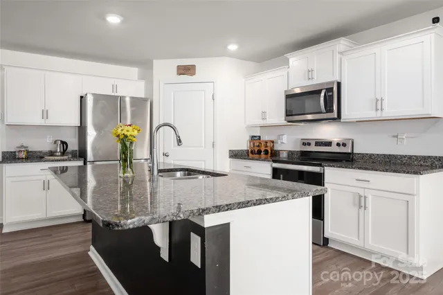 a kitchen with stainless steel appliances granite countertop a sink a stove and cabinets