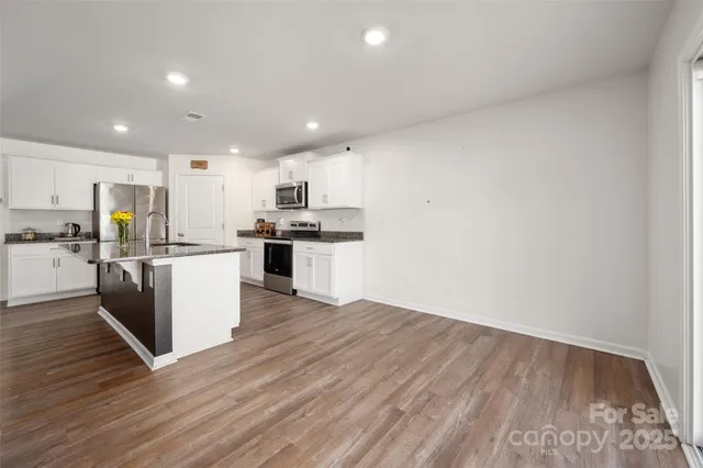 a kitchen with wooden floors and white stainless steel appliances