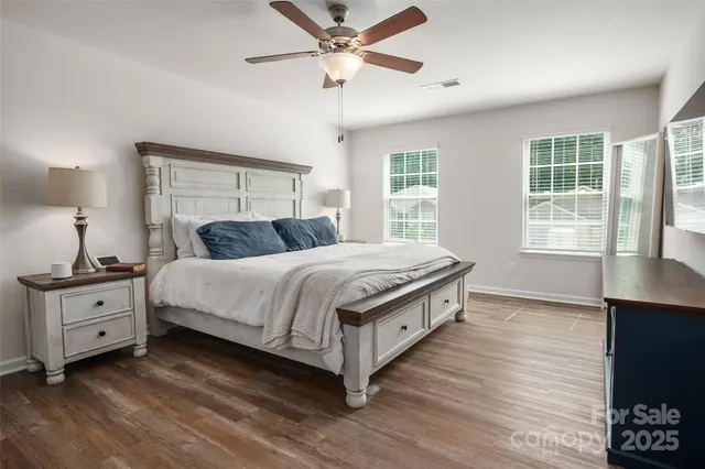 a bedroom with a bed and a ceiling fan with wooden floor