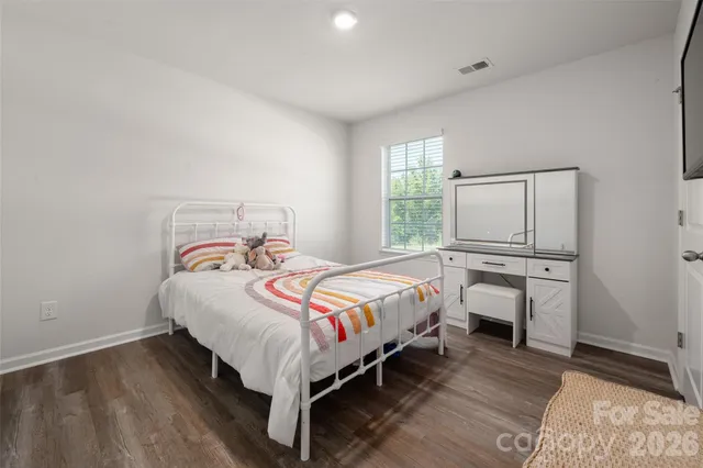 a bedroom with a bed a mirror on dresser and a window