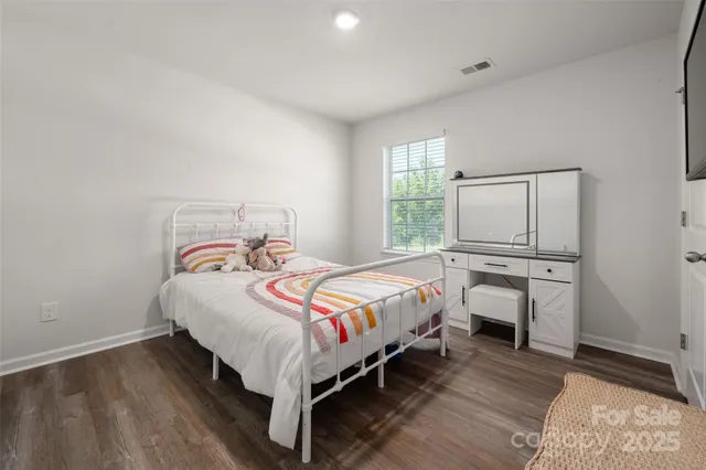 a bedroom with a bed a mirror on dresser and a window