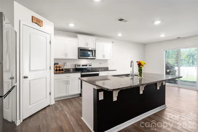 a kitchen with kitchen island granite countertop a sink appliances and cabinets