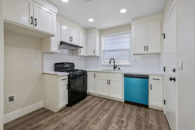 a kitchen with stainless steel appliances white cabinets a sink a stove a refrigerator and cabinets