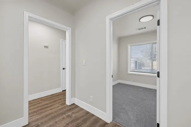a view of an empty room with wooden floor and a mirror