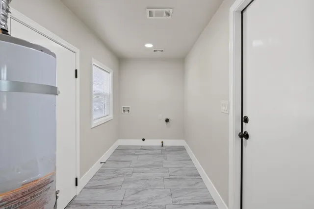 a view of a hallway with wooden floor and a bathroom