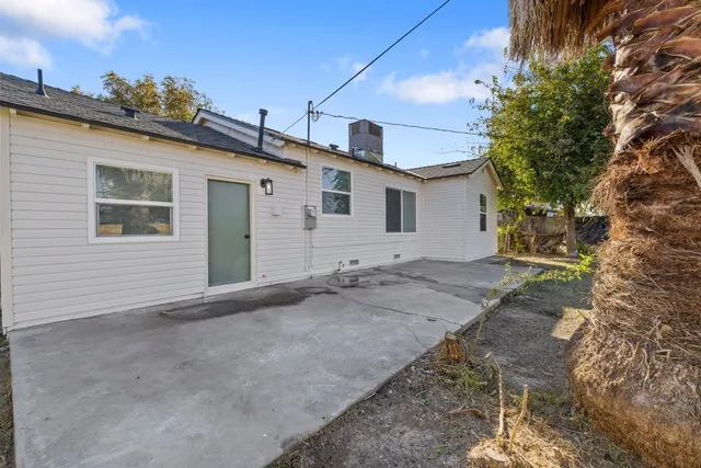 a view of a house with a small yard and a large tree