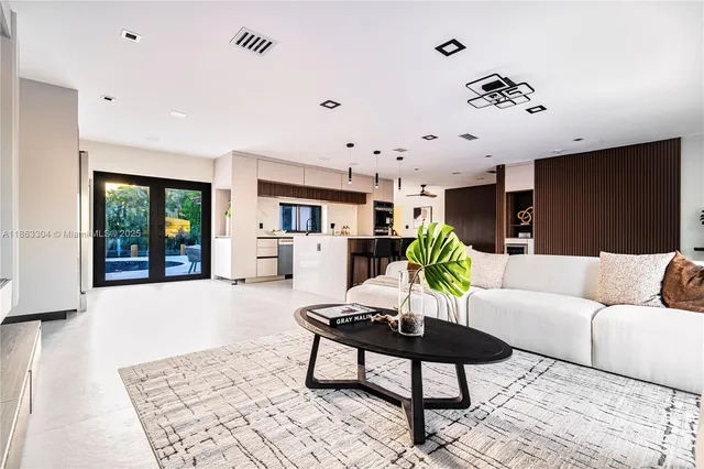 a living room with furniture a chandelier and kitchen view