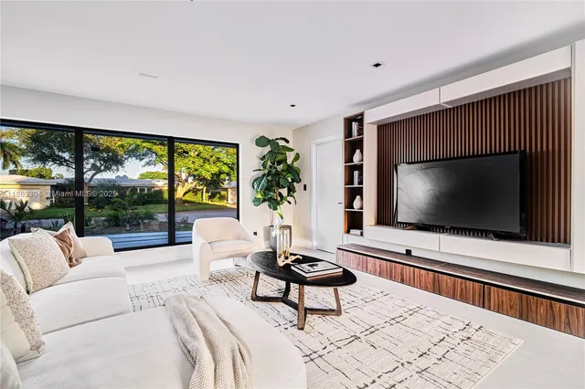 a living room with furniture a floor to ceiling window and a flat screen tv