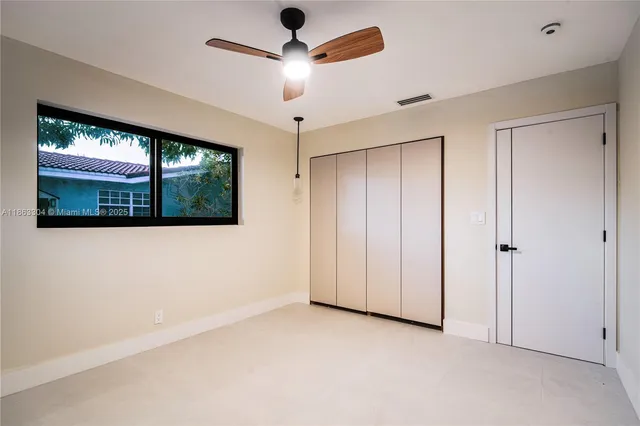 a view of empty room with window and ceiling fan