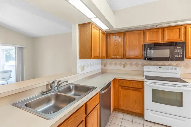 a kitchen with granite countertop a sink stove top oven and refrigerator