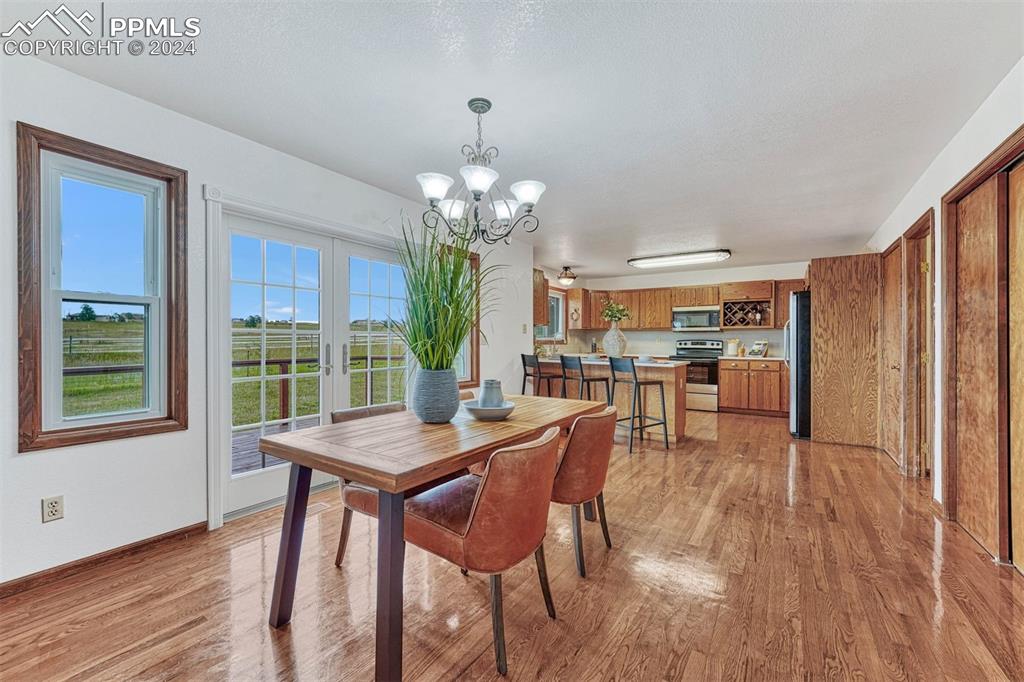 12220 Old Barn Road Elbert, CO 80106 - Photo 17 of 47 a dining room with furniture a chandelier and wooden floor
