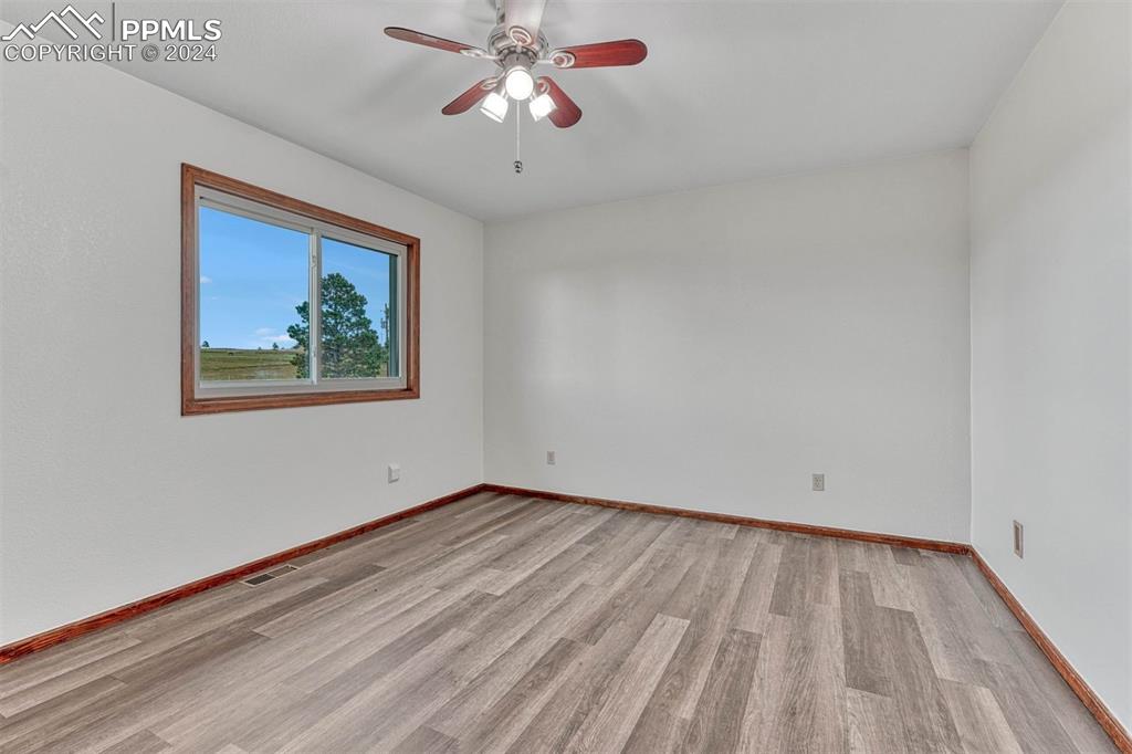 12220 Old Barn Road Elbert, CO 80106 - Photo 31 of 47 a view of an empty room with wooden floor and a chandelier fan