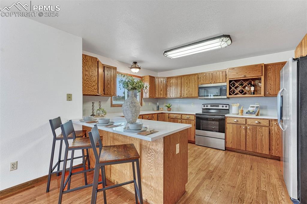12220 Old Barn Road Elbert, CO 80106 - Photo 4 of 47 a kitchen with stainless steel appliances kitchen island granite countertop a sink dishwasher a stove a refrigerator with island and chairs with wooden floor