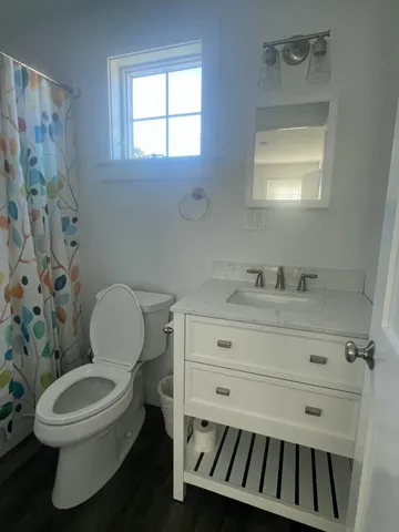 a bathroom with a toilet a sink a mirror and a window