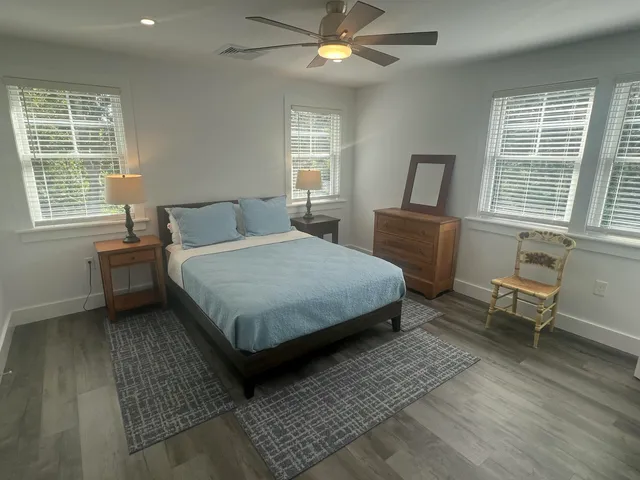 a bedroom with a bed wooden floor and windows