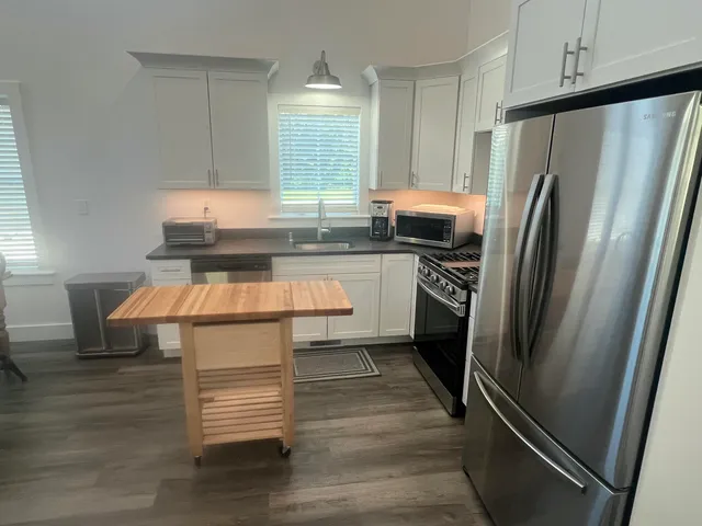 a kitchen with kitchen island a counter top space a refrigerator and a sink