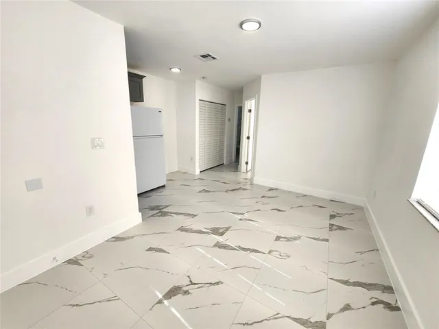 a view of a hallway with wooden floor and a refrigerator