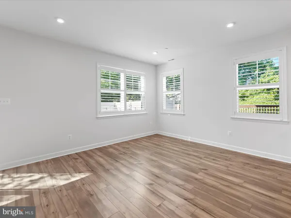 a view of an empty room with wooden floor fireplace and a window