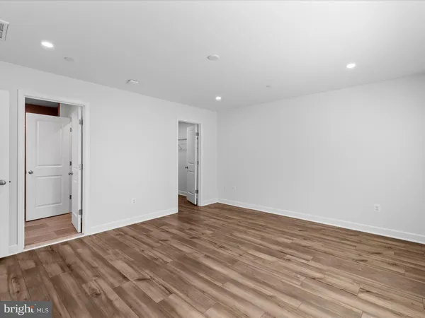 a spacious bedroom with a bed and wooden floor