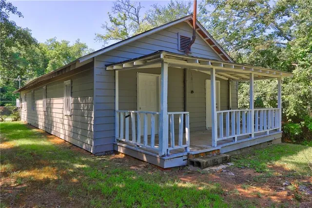 a view of a small house with a small yard and wooden fence