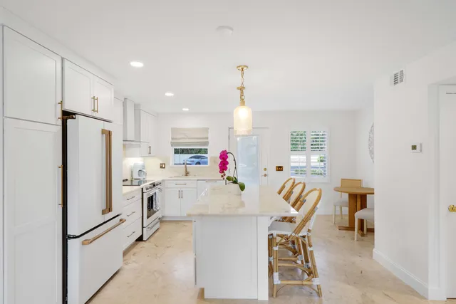 a kitchen with stainless steel appliances kitchen island granite countertop a refrigerator and a dining table