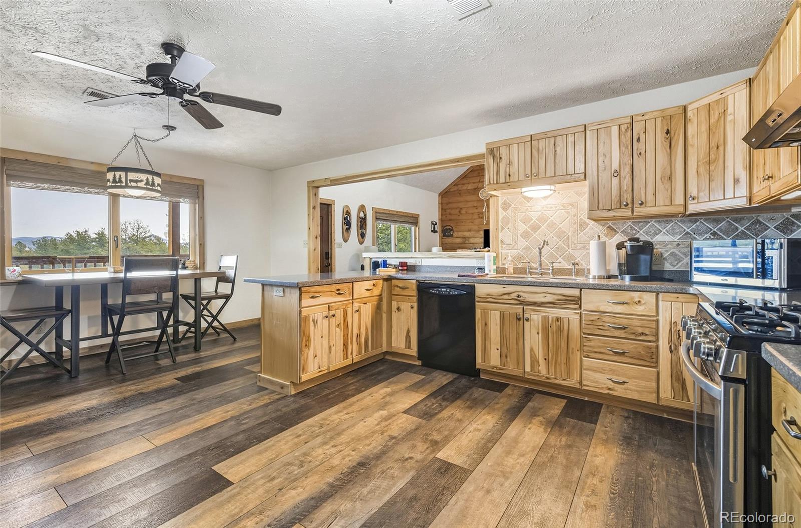 111 Twinkle Road Guffey, CO 80820 - Photo 16 of 39 a kitchen with a stove a sink dishwasher a dining table and chairs with wooden floor